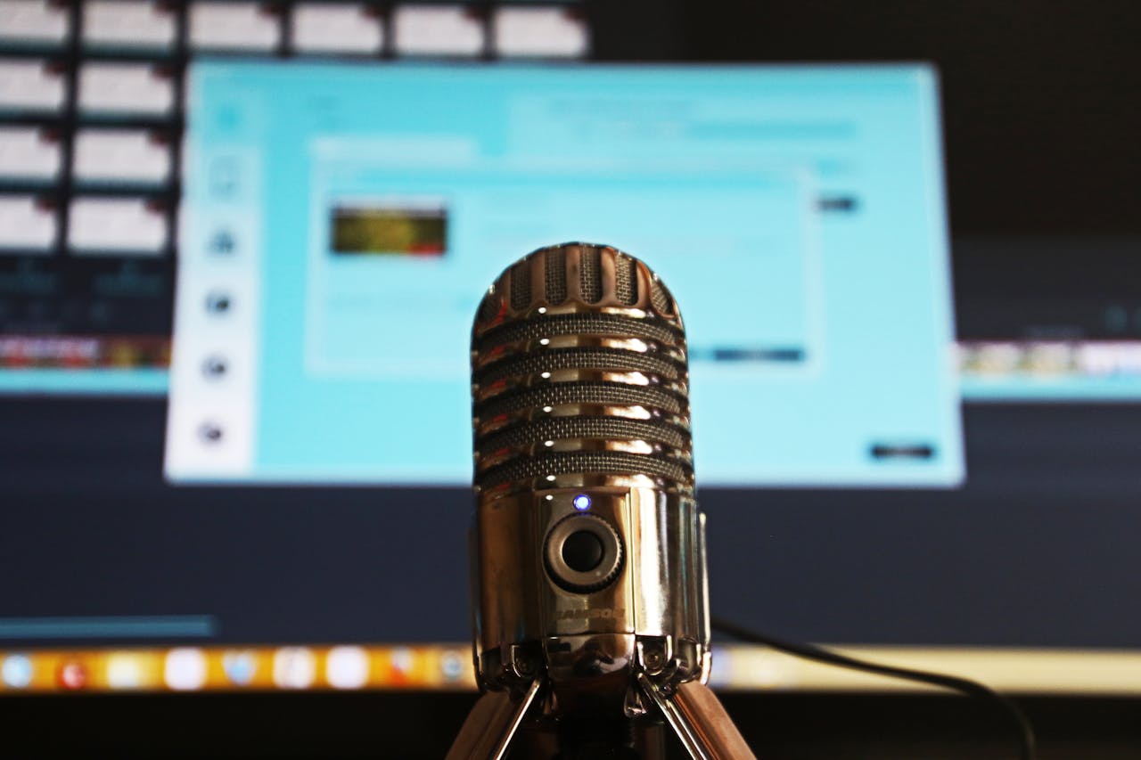service-06 Close-up of a microphone with a blurred computer screen in the background, ideal for podcast themes.