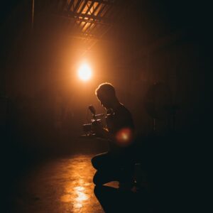 Silhouette of a cinematographer operating a camera in a dimly lit studio with dramatic lighting.