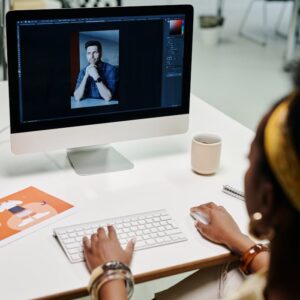 Woman working on photo editing with a desktop computer in a modern office setting.