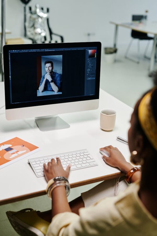 Woman working on photo editing with a desktop computer in a modern office setting.