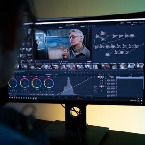 Sound engineer editing film using professional software in a dimly lit studio.